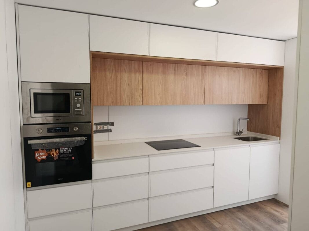Cocina moderna a medida con muebles blancos mate y toques de madera en Murcia - Alitor Carpinteros